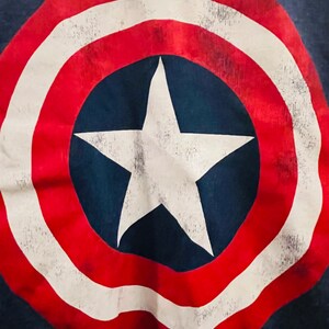 Puede incluir: Una estrella roja, blanca y azul sobre un fondo azul marino. La estrella est&aacute; dentro de un c&iacute;rculo con rayas rojas y blancas alternas. El dise&ntilde;o recuerda a la bandera estadounidense.