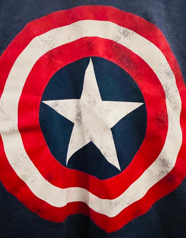 Puede incluir: Una estrella roja, blanca y azul sobre un fondo azul marino. La estrella est&aacute; dentro de un c&iacute;rculo con rayas rojas y blancas alternas. El dise&ntilde;o recuerda a la bandera estadounidense.