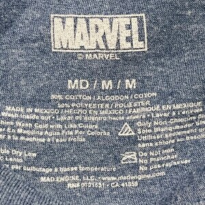 Puede incluir: Una camiseta azul de algod&oacute;n y poli&eacute;ster con un logotipo blanco de Marvel e instrucciones de cuidado. La etiqueta dice "MD/M/M", "50% Algod&oacute;n/Algodon/Coton", "50% Poli&eacute;ster/Poliester", "Hecho en M&eacute;xico/Hecho en Mexico/Fabrique en Mexique", "Lavar a m&aacute;quina con agua fr&iacute;a con colores similares", "Solo blanqueador sin cloro", "Secar en secadora a baja temperatura", "No planchar", "Mad Engine, LLC, www.madengine.com", "RN# 0731631-CA 41859".