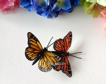 May include: Two orange and black butterflies with white spots on their wings are on a white background. The butterflies are facing each other and their wings are spread out.