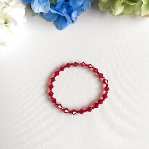 May include: A red crystal bracelet with faceted beads. The bracelet is on a white background.