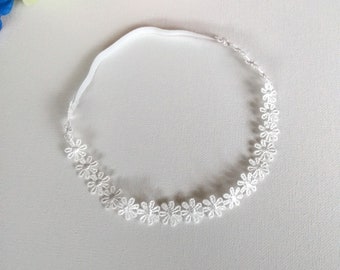 May include: White lace headband with a delicate floral design. The headband is made of a soft, stretchy material and is perfect for adding a touch of elegance to any outfit.