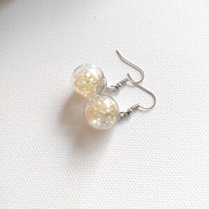 May include: A pair of silver dangle earrings with clear glass orbs filled with iridescent glitter.