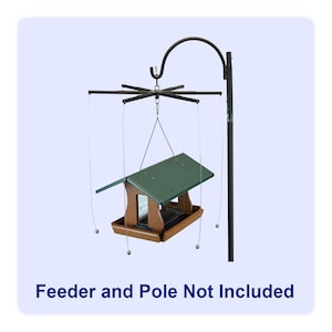 Op de afbeelding: Een zwarte metalen paal met een roterend hulpstuk met zes armen. Dunne draden met kleine metalen gewichtjes hangen aan elke arm om een bruine en groene vogelvoederbak te ondersteunen. De tekst Feeder and Pole Not Included is zichtbaar.