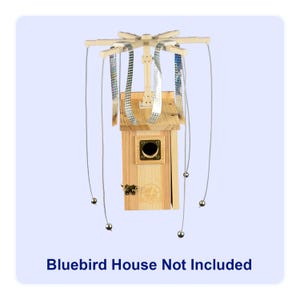 May include: A wooden birdhouse with a decorative top and hanging silver-colored wires with small silver balls. The birdhouse has a small door and a circular opening. The text "Bluebird House Not Included" is at the bottom.