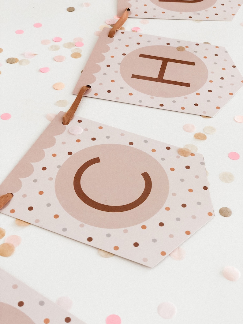 May include: A brown and white banner with the letters "CH" in a circle on each flag. The flags are decorated with small brown, white and pink polka dots.