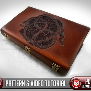 Puede incluir: Un diario encuadernado en cuero marrón con un diseño en relieve detallado de un dragón celta en nudos. El diario tiene detalles en latón en el lomo.