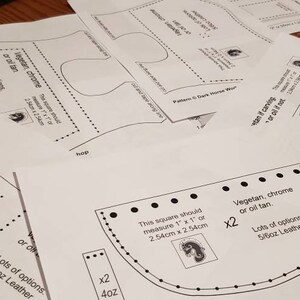 K&ouml;nnte beinhalten: Ein Satz Lederbearbeitungsmuster f&uuml;r ein Dark Horse Workshop-Projekt. Die Muster sind auf wei&szlig;em Papier gedruckt und enthalten Anweisungen zum Zuschneiden und Zusammensetzen der Lederteile. Die Muster umfassen ein Quadrat, eine geschwungene Form und ein Design mit einem keltischen Knoten.