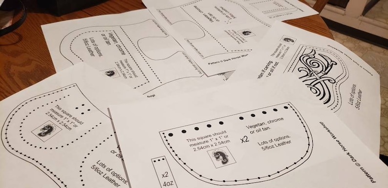 K&ouml;nnte beinhalten: Ein Satz Lederbearbeitungsmuster f&uuml;r ein Dark Horse Workshop-Projekt. Die Muster sind auf wei&szlig;em Papier gedruckt und enthalten Anweisungen zum Zuschneiden und Zusammensetzen der Lederteile. Die Muster umfassen ein Quadrat, eine geschwungene Form und ein Design mit einem keltischen Knoten.