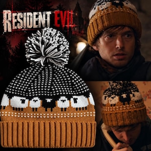 May include: A knit beanie featuring a mustard yellow ribbed cuff and a pattern of white and black sheep across the centre. The top section is black with white speckles, topped with a large, fluffy black and white pom-pom. The text Resident Evil is visible.