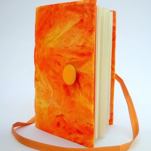 May include: Orange velvet journal with a yellow button closure and an orange ribbon strap.