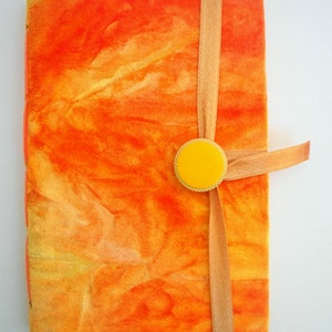 May include: Orange and yellow handmade journal with a yellow button and a tan ribbon.