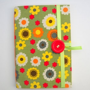 May include: A green fabric notebook with a floral pattern in shades of yellow, orange, red, and gray. The notebook has a green ribbon closure and a red button.