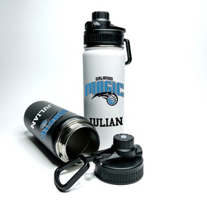 May include: Two black and white water bottles with a black lid and a carrying loop. One bottle has the Orlando Magic logo and the name "JULIAN" printed on it. The other bottle has the name "JULIAN" printed on it.
