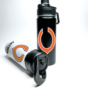 May include: Two stainless steel water bottles with a black and white design featuring the Chicago Bears logo. The logo is a stylized orange "C" with a navy blue outline.