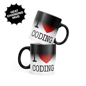 May include: Two black ceramic mugs with a heat-changing feature. The mugs display a white base that transitions to black at the top. Each mug features the text I, a red heart symbol, and the word CODING in black capital letters on the white area.