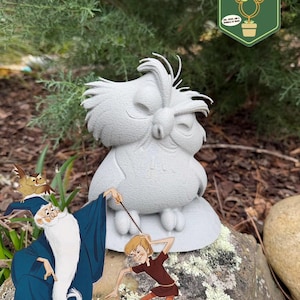 May include: A gray owl statue with closed eyes sits on a rock, with cartoon illustrations of characters from a classic animated film. The image includes a green and white logo that says "Pixie Dust Gardening".