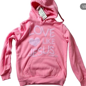 Könnte beinhalten: Rosafarbener Hoodie mit einem weißen gestickten Herzen und den Worten "Love Like Jesus 1 John 4:19"