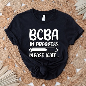 May include: Black t-shirt with white text that reads "BCBA in progress" with a progress bar and the words "Please wait..."