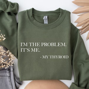 May include: A green sweatshirt with the text "I'M THE PROBLEM. IT'S ME. - MY THYROID" printed in white.