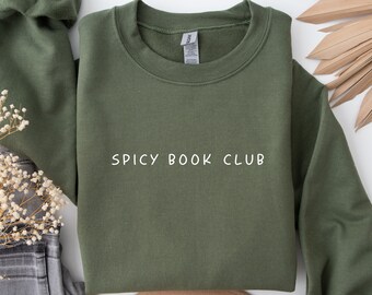 May include: A green sweatshirt with the text "Spicy Book Club" printed in white on the front.