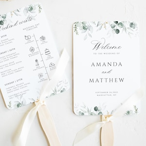 May include: A white wedding fan with green foliage and a wedding timeline on one side and a welcome message for Amanda and Matthew on the other side. The fan is made of paper and has a wooden handle.
