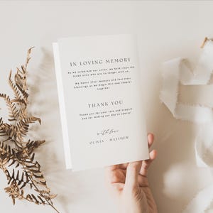 Op de afbeelding: Een witte kaart met de tekst "In Loving Memory" en "Thank You" gedrukt in zwart. De kaart bevat ook de tekst "with love" en de namen "Olivia" en "Matthew".
