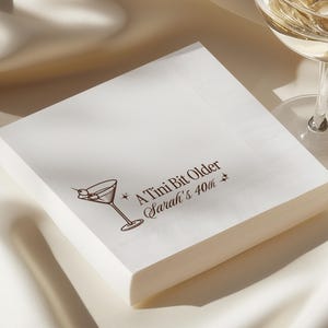 Custom cocktail napkins for 40th birthday celebration, A Tini Bit Older martini style design with name and age personalization. Elegant white 3 ply napkins in cocktail or luncheon size, available in ink colors black, hot pink, navy, or espresso. Fun party décor for milestone events.