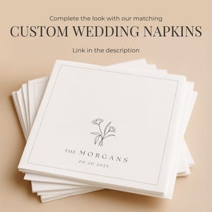 May include: A stack of square white paper napkins featuring a thin black border, a small line-art floral illustration, and the text "THE MORGANS" followed by the date "09.20.2025". The top text reads "Complete the look with our matching CUSTOM WEDDING NAPKINS" and "Link in the description".