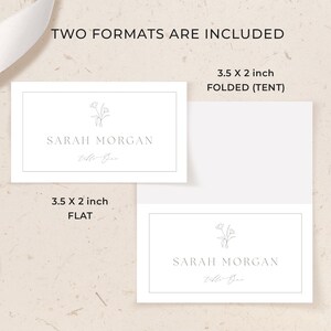 May include: Two white rectangular place cards featuring a thin border, a small line-art floral illustration, and the printed text Sarah Morgan and Table One. One card is flat, and the other is folded into a tent shape, both measuring 3.5 x 2 inches.