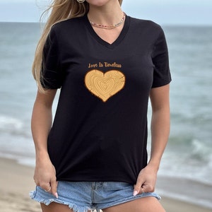 May include: Black v-neck t-shirt with a wood grain heart graphic and the text "Love Is Timeless".