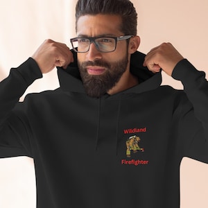 May include: Black hooded sweatshirt with a red embroidered design of a firefighter with the text "Wildland Firefighter" on the front.
