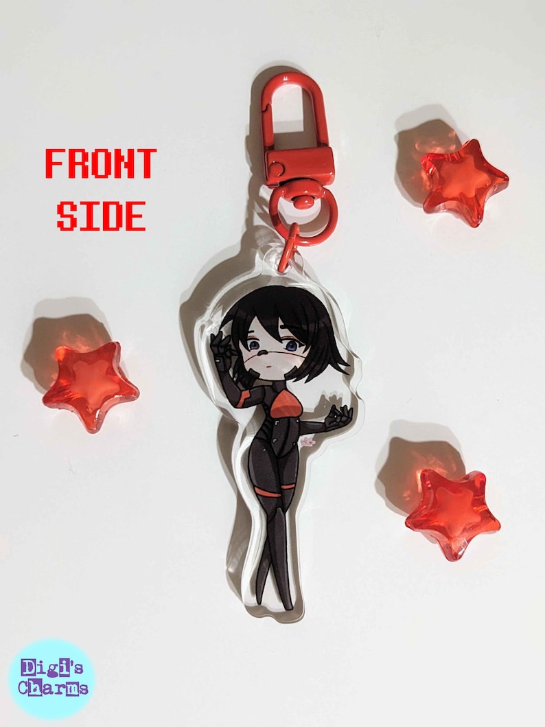 K&ouml;nnte beinhalten: Ein durchsichtiger Acryl-Schl&uuml;sselanh&auml;nger mit einer Cartoon-Anime-Figur mit schwarzen Haaren, einem rot-schwarzen Outfit und einer rot-schwarzen Gesichtsmaske. Der Schl&uuml;sselanh&auml;nger hat einen roten Metallverschluss. Der Hintergrund ist wei&szlig; mit drei roten sternf&ouml;rmigen Objekten.