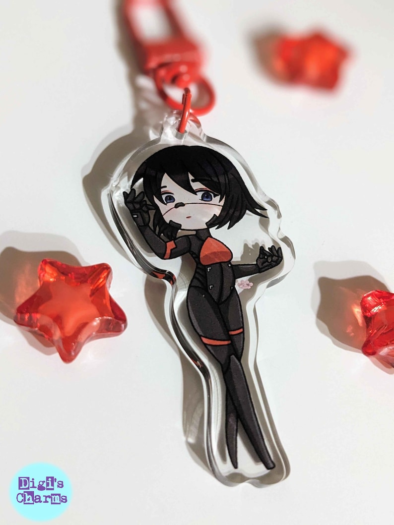 K&ouml;nnte beinhalten: Ein durchsichtiger Acryl-Schl&uuml;sselanh&auml;nger mit einer Cartoon-Anime-Figur mit schwarzen Haaren, einem rot-schwarzen Outfit und einer wei&szlig;en Gesichtsmaske. Die Figur steht mit einer erhobenen Hand. Der Schl&uuml;sselanh&auml;nger ist von roten sternf&ouml;rmigen Objekten umgeben.