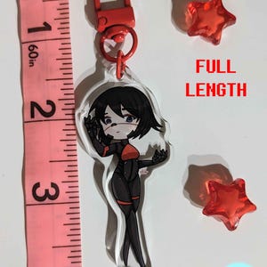 K&ouml;nnte beinhalten: Ein roter und schwarzer Anime-Charakter-Schl&uuml;sselanh&auml;nger mit einem klaren Acryl-Anh&auml;nger. Der Schl&uuml;sselanh&auml;nger ist an einem roten Metallverschluss befestigt. Der Charakter ist eine Frau mit schwarzen Haaren und einem roten und schwarzen Outfit. Der Schl&uuml;sselanh&auml;nger ist etwa 7,6 cm lang.
