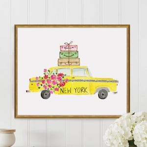 May include: Watercolor print of a yellow New York City taxi cab with luggage on top and a floral arrangement. The framed artwork has a gold border and is displayed on a white wall.