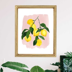 May include: A framed watercolor print featuring a branch of lemons with green leaves against a pink background. The artwork is displayed in a gold-colored frame, adding a touch of elegance to the botanical theme.