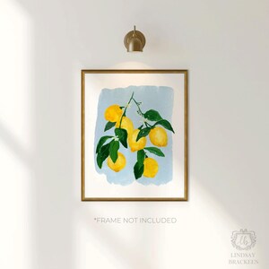 K&ouml;nnte beinhalten: Ein gerahmter Aquarelldruck mit gelben Zitronen an einem Zweig mit gr&uuml;nen Bl&auml;ttern und wei&szlig;en Bl&uuml;ten. Die Zitronen sind vor einem hellblauen Hintergrund platziert. Der Rahmen ist goldfarben. Der Text "*FRAME NOT INCLUDED" steht unten.