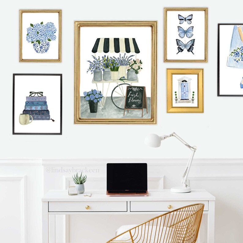 May include: A white desk with a gold chair and a laptop computer. There are five framed pictures on the wall above the desk. The pictures are of flowers, butterflies, a door, and books. The text on the sign in the picture reads "Fresh Flowers".
