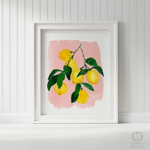 Op de afbeelding: Een ingelijste kunstdruk met een aquarelillustratie van een citroentak met vijf felgele citroenen en donkergroene bladeren, gecentreerd op een zachtroze rechthoekige achtergrond in een strakke witte lijst.