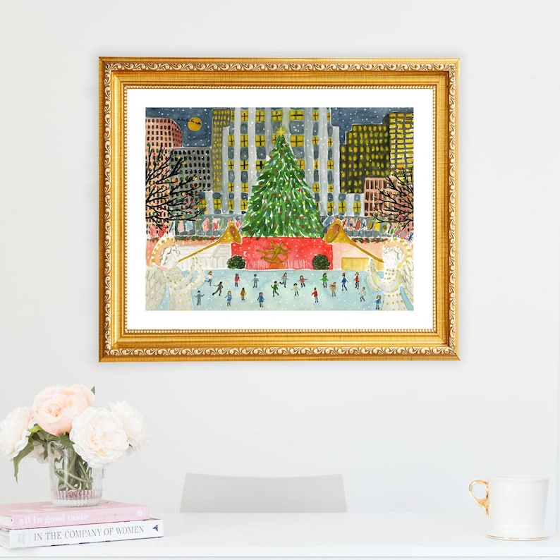 Puede incluir: Una pintura al agua enmarcada que representa una escena de ciudad nevada con un gran &aacute;rbol de Navidad en el centro. El &aacute;rbol est&aacute; decorado con luces y adornos. La gente patina sobre hielo frente al &aacute;rbol. Los edificios en el fondo son altos y tienen ventanas iluminadas. La pintura est&aacute; en un marco dorado.