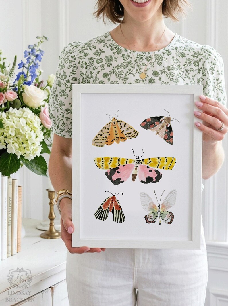 Puede incluir: Una l&aacute;mina art&iacute;stica enmarcada que presenta cinco ilustraciones de polillas en estilo acuarela. Las polillas muestran patrones y colores variados, incluyendo tonos amarillos, rosas, negros, naranjas y blancos, dispuestos verticalmente sobre un fondo blanco.