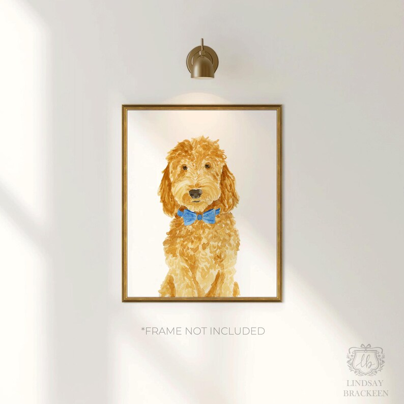 May include: A framed watercolor print of a golden-colored doodle dog with curly fur, wearing a bright blue bow tie around its neck. The artwork is centered within a gold-toned frame and features the text "FRAME NOT INCLUDED" at the bottom.