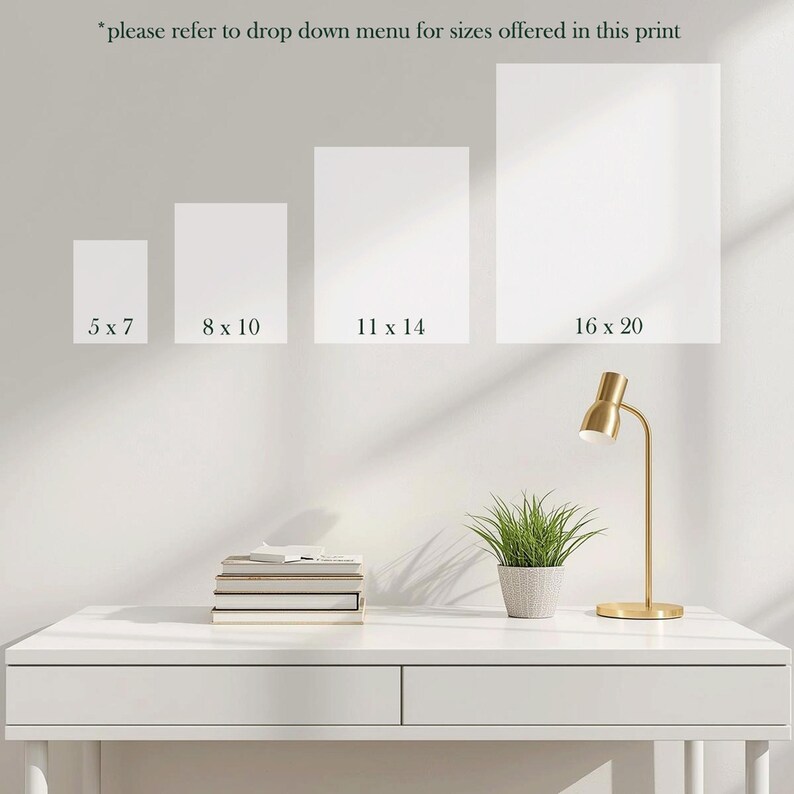 May include: Four white rectangular art prints in varying sizes: 5 x 7 inches, 8 x 10 inches, 11 x 14 inches, and 16 x 20 inches. The text "*please refer to drop down menu for sizes offered in this print" is at the top. A gold desk lamp and a potted plant sit on a white desk.
