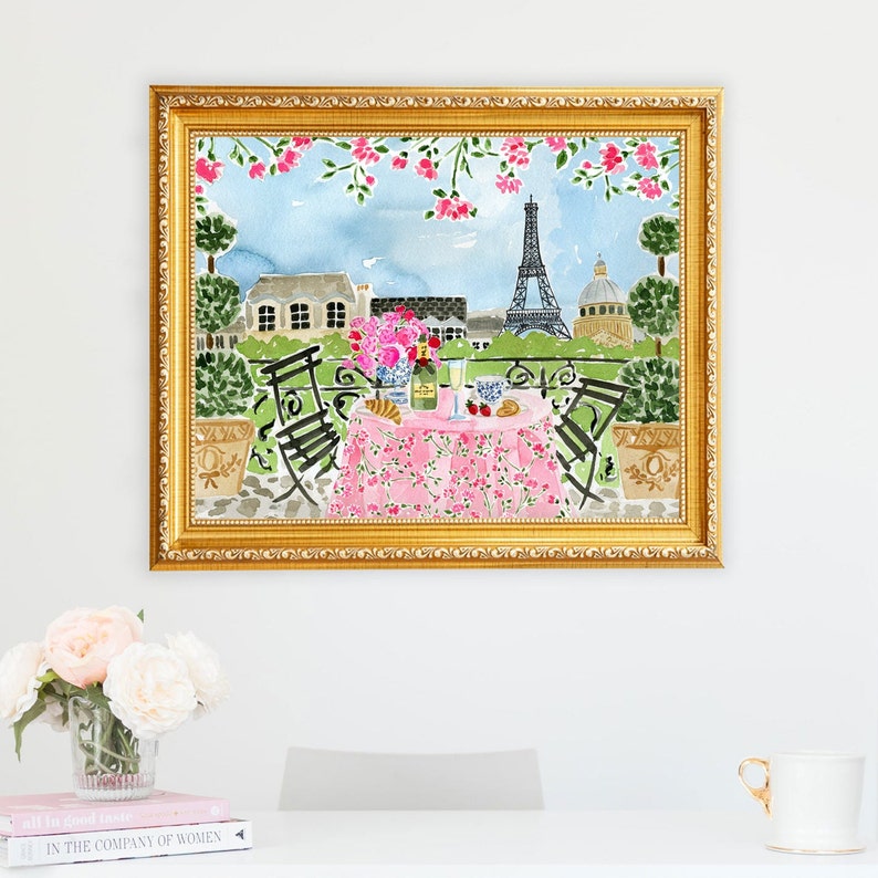 May include: A watercolor painting of a Parisian cafe scene with a pink tablecloth, two chairs, and a bottle of champagne. The Eiffel Tower is visible in the background.
