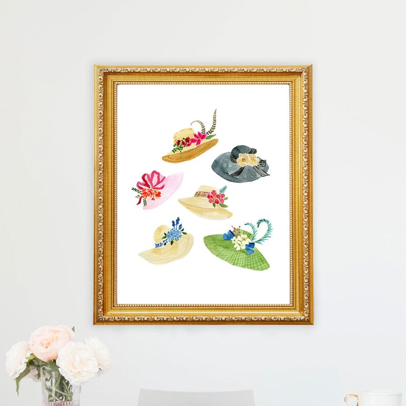 May include: A framed print of six watercolour illustrations of different hats with floral embellishments. The hats are in various colours, including pink, green, blue, and yellow.