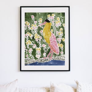 May include: Framed watercolor print of a bird with yellow and pink plumage, black head, and long beak. The bird stands on a leopard-print surface above a blue area, set against a backdrop of green foliage and yellow and pink flowers.