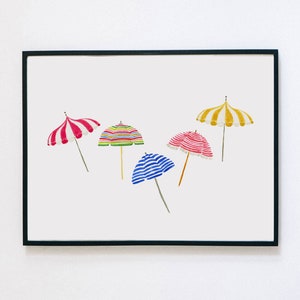 May include: A framed print featuring watercolor illustrations of five beach umbrellas. The umbrellas have various designs, including red and white stripes, colorful horizontal stripes, and blue and white stripes. One umbrella has yellow and white stripes.