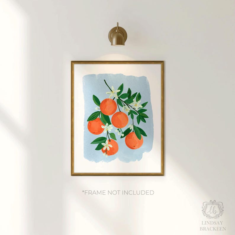 K&ouml;nnte beinhalten: Ein gerahmter Kunstdruck mit einer Aquarellillustration von Orangen auf einem Ast mit gr&uuml;nen Bl&auml;ttern und wei&szlig;en Bl&uuml;ten vor einem hellblauen Hintergrund. Der Rahmen ist goldfarben. Der Text unten lautet "FRAME NOT INCLUDED".