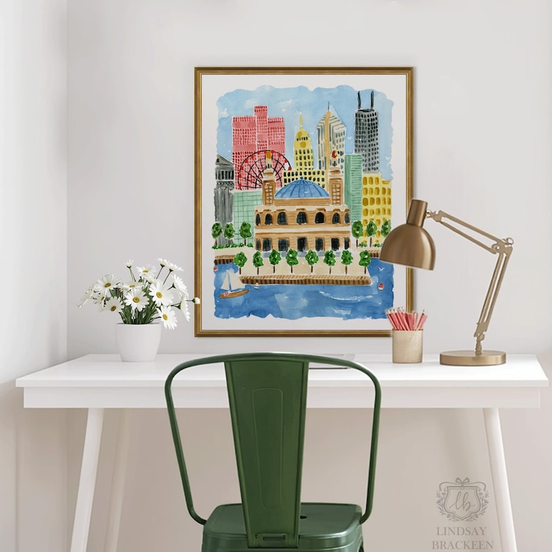 May include: A framed watercolor print of a city skyline featuring a prominent domed building, a red ferris wheel, and various skyscrapers in shades of red, yellow, and blue, set against a light blue sky above a dark blue body of water.